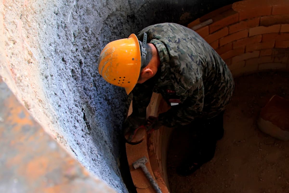 Worker placing refractory bricks in a furnace lining
