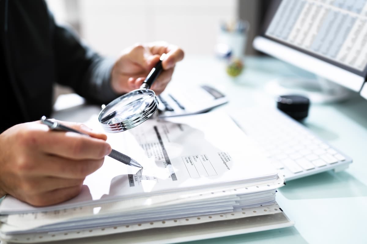 Person looking at data in a stack of documents using a magnifier